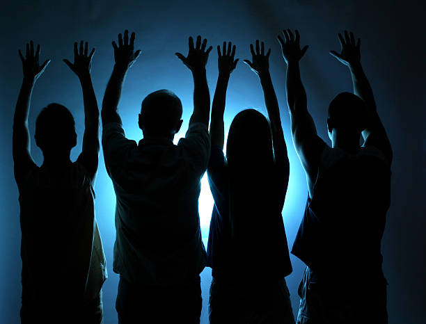 Four people offering praise or worship.   Spirituality. Blue light background. ...